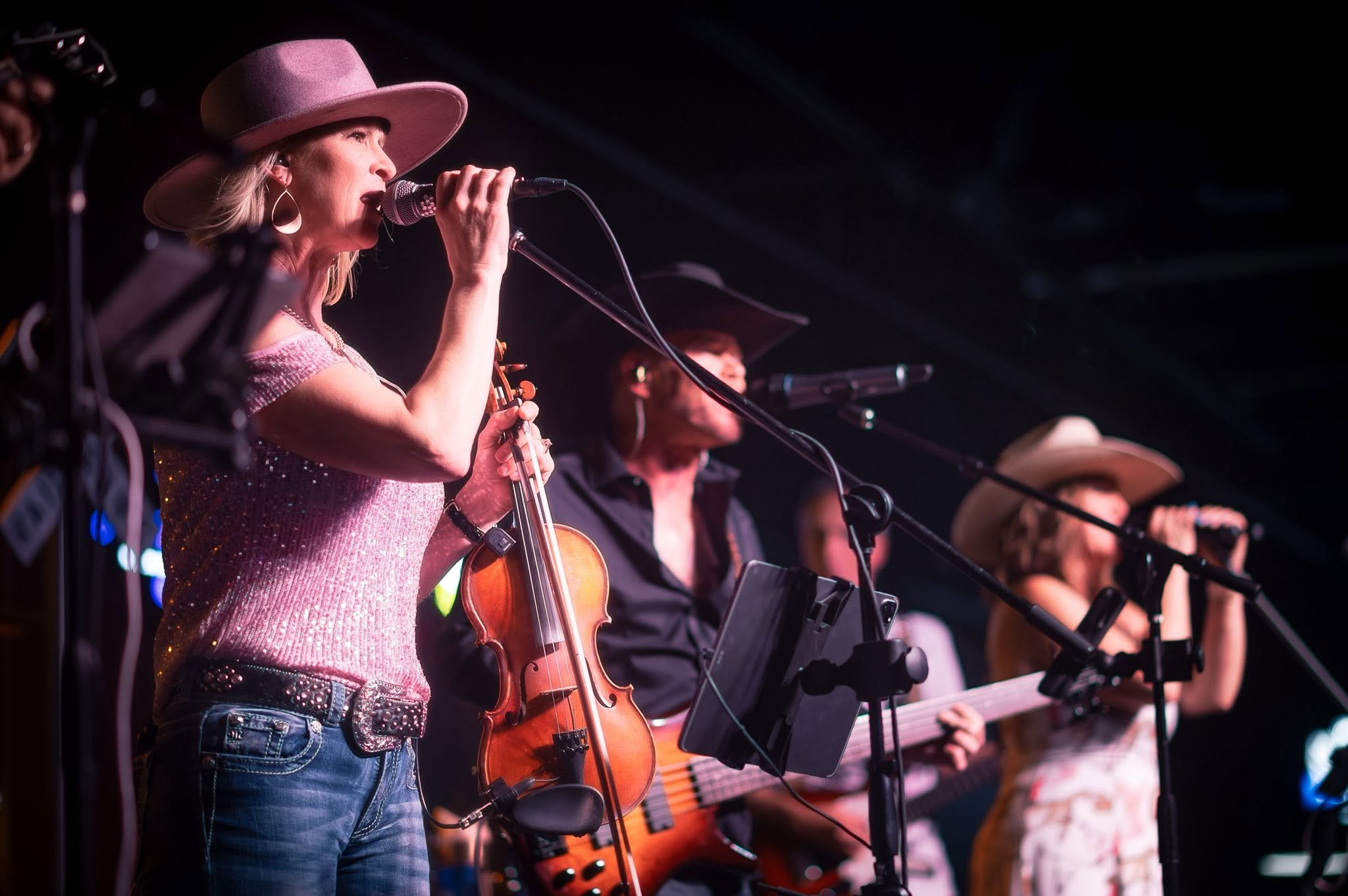 Runaway Train singers and fiddle player mid-song under stage lights